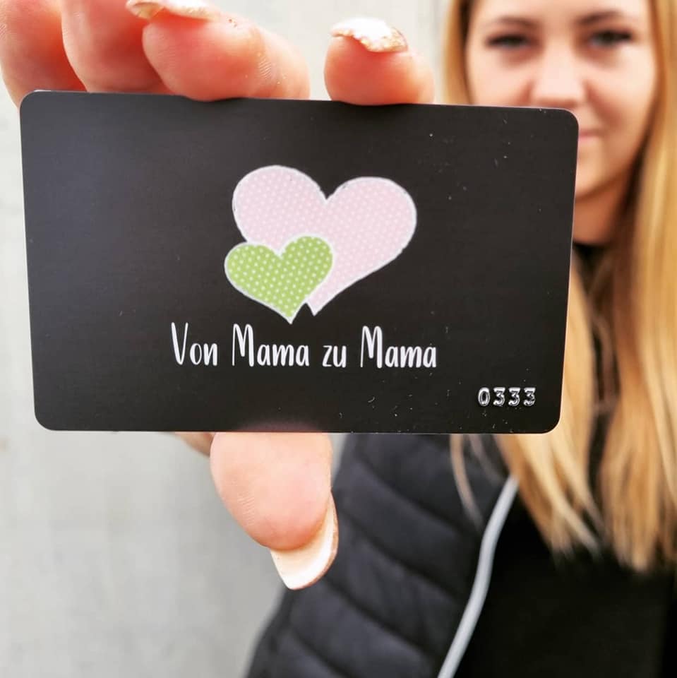 eine blonde Frau hält die von Mama zu Mama Membercard in der Hand. 